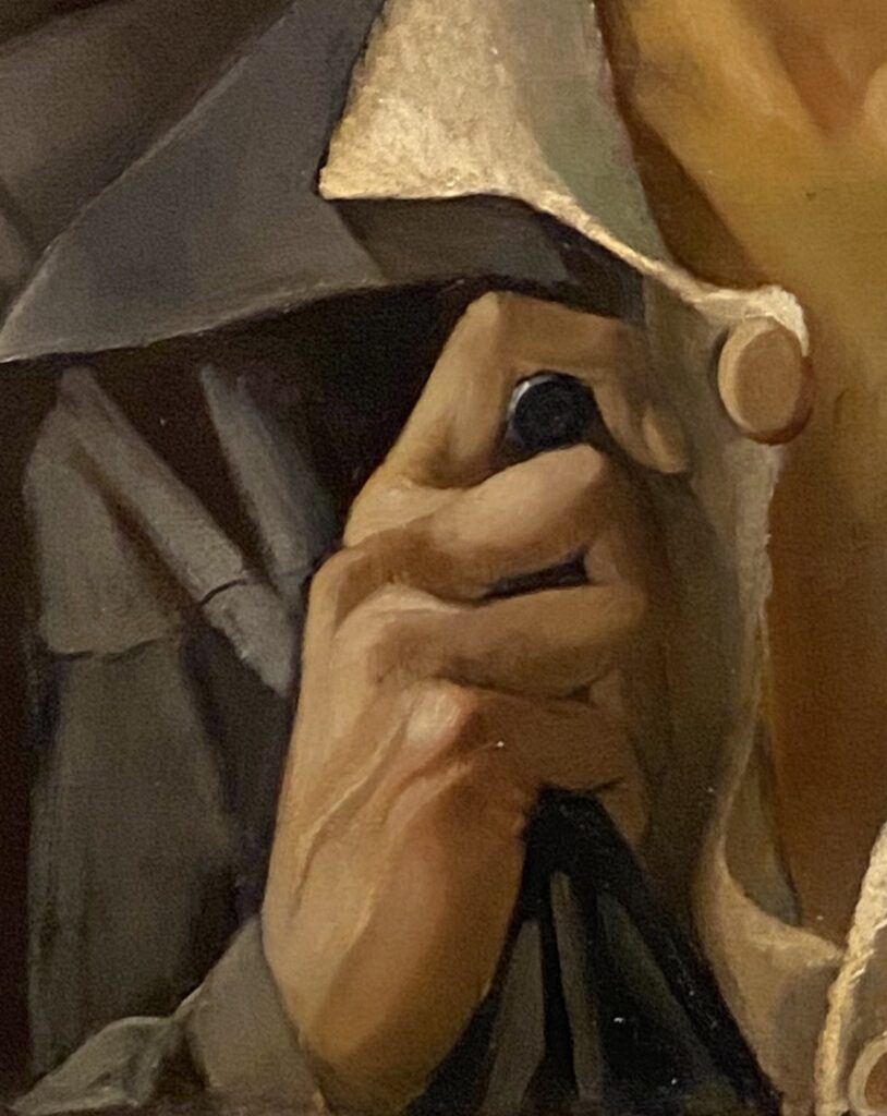 Detail van de hand op een hiervoor genoemd schilderij: een wijsvinger omklemt de bovenste knoop van een grijsblauw jasje, gedragen over een witte blouse